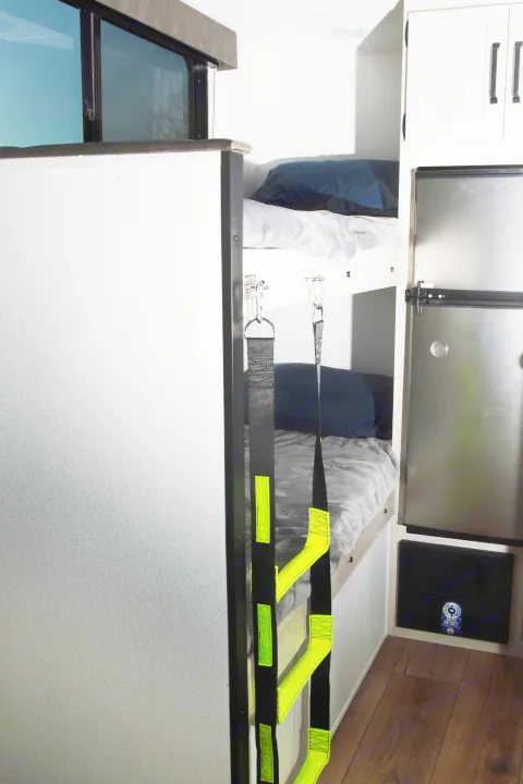 An RV rental interior featuring cozy bunk beds with a bright ladder, a refrigerator, and storage cabinets for comfortable family travel.. Palomino Puma Camping Edition 122BHCE 2026