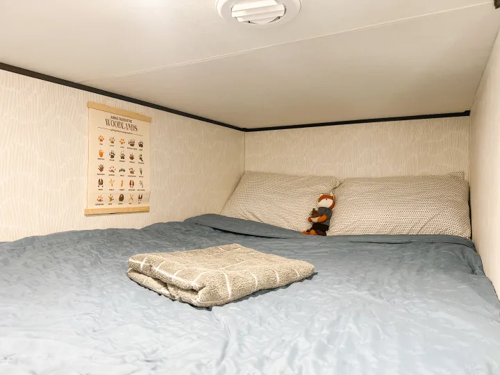 Cozy RV rental bed with a fun animal tracks poster and soft blue bedding, featuring a cute fox toy in a comfortable nook.. Jayco Jay Flight SLX 2024