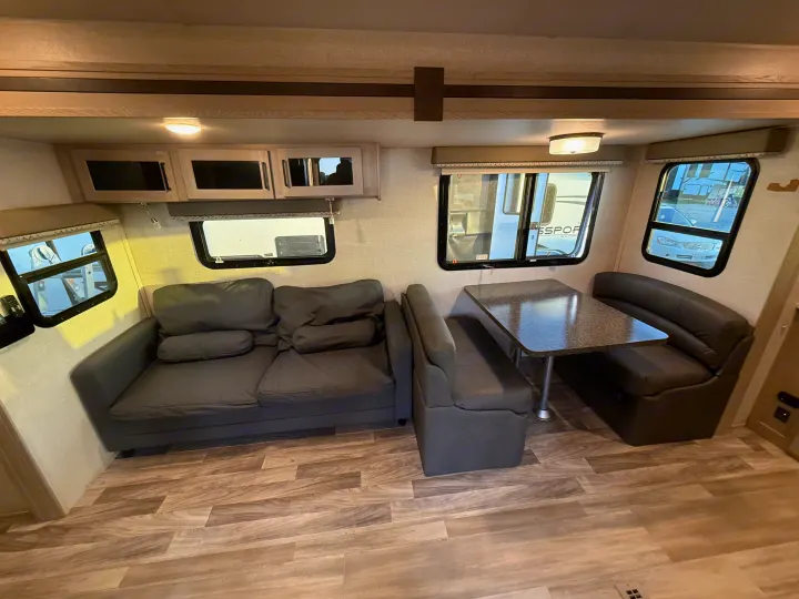 Spacious RV rental living area featuring a dark grey sofa, dinette, and overhead storage cabinets.. Forest River Flagstaff Super Lite 2021