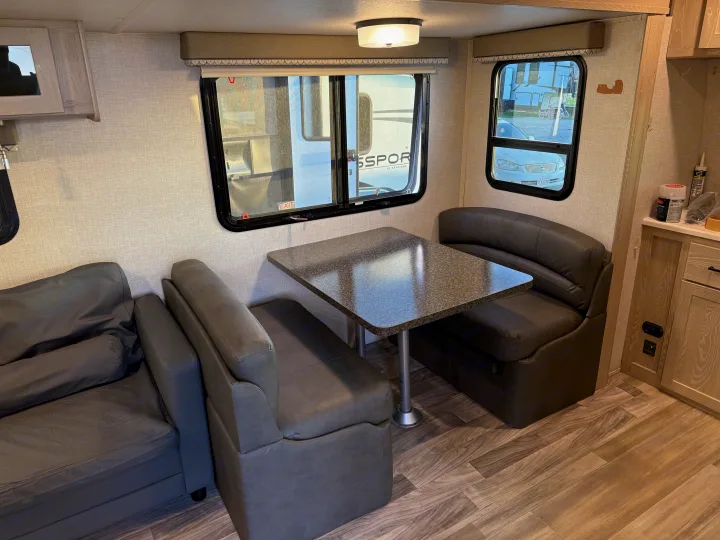 Inside this RV rental, a cozy living area features a dinette with dark seating, a table, and a sofa, alongside light wood accents.. Forest River Flagstaff Super Lite 2021
