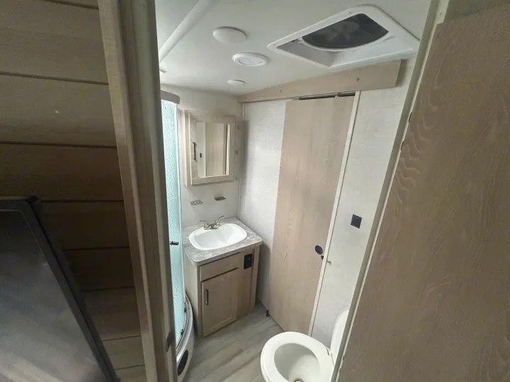 Modern RV rental bathroom showcasing a compact design with sink, mirror, shower stall, and toilet for convenience.. Forest River Flagstaff Super Lite 2021