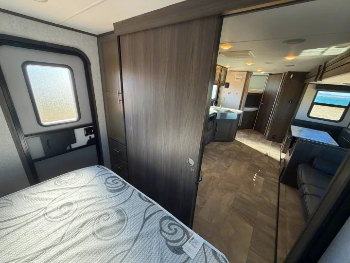 Modern RV rental interior: bedroom, sliding door to kitchen, dining area, and a scenic window view.. Dutchmen Kodiak Ultra Lite 2021