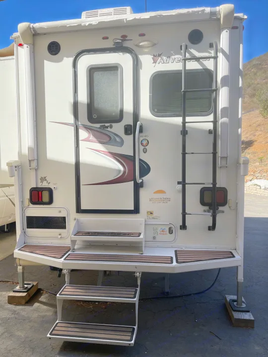 Rear view of an Adventurer truck camper RV rental with extended steps, ladder, and awning. Ready for adventure!. Adventurer Lp Adventurer 2016