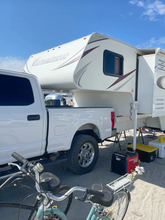 Adventurer truck camper on a Ford pickup, set up on sand with bikes and a generator. Perfect for an RV rental adventure!. Adventurer Lp Adventurer 2016