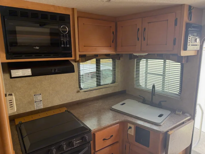 This rv rental kitchen features a High Pointe microwave, Suburban stove, sink, and wood cabinets. Everything needed for your trip!. Adventurer Lp Adventurer 2016