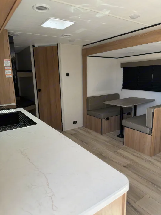 Inside a bright **rv rental**: modern kitchen counter, comfortable dinette, and cozy bunk beds visible in the background.. Keystone Coleman 2026
