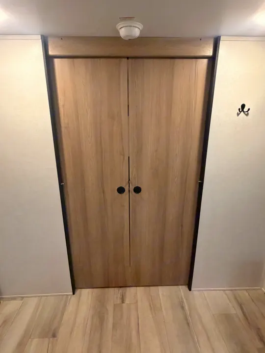 Modern RV rental interior featuring light wood closet doors, matching flooring, and a safety detector. Efficient storage solution.. Keystone Coleman 2026