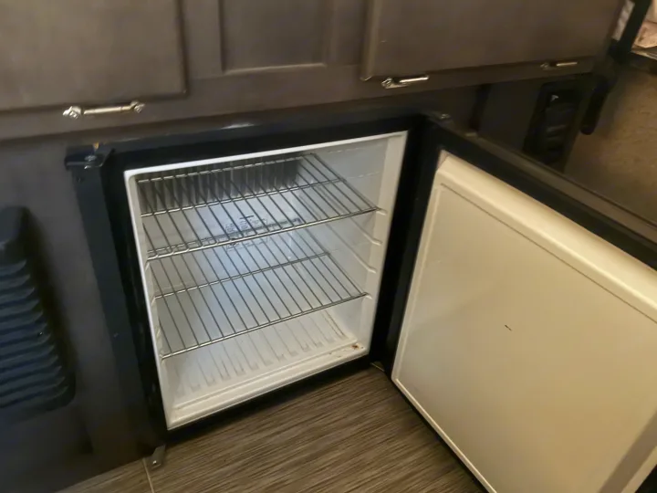 An open, empty mini-fridge with wire shelves in an rv rental. Ready for your trip supplies.. Forest River Flagstaff 2020