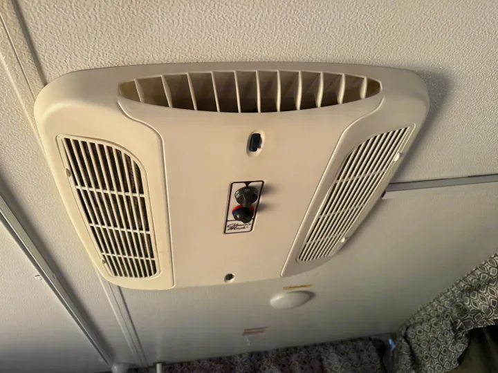 This rv rental overhead AC unit, a Coleman-Mach, shows controls for fan speeds and cooling, with vents on a textured ceiling.. Forest River Flagstaff 2020