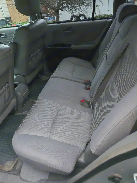 Clean car interior with gray seats & rubber mats. A white trailer outside may be an RV rental.. Toyota Highlander 2004