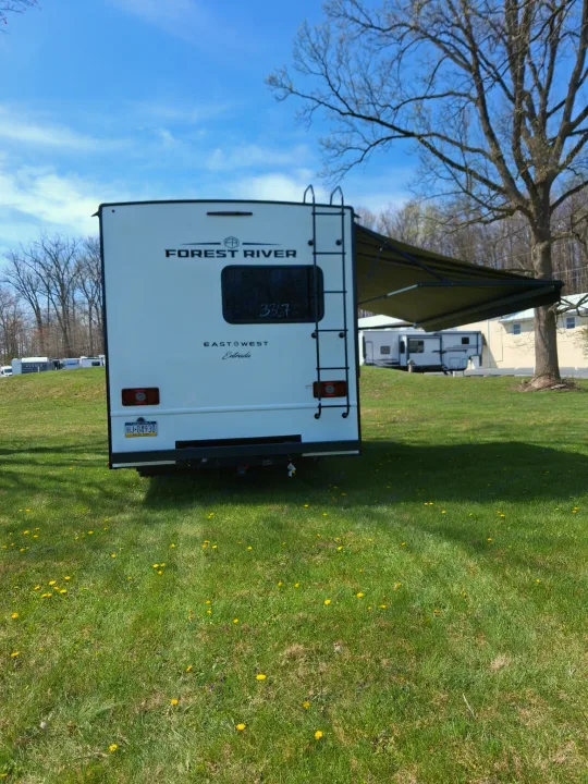 This Forest River East to West Entrada rv rental sits on a sunny, grassy site, ready for travel and camping.. East to West Entrada 2026