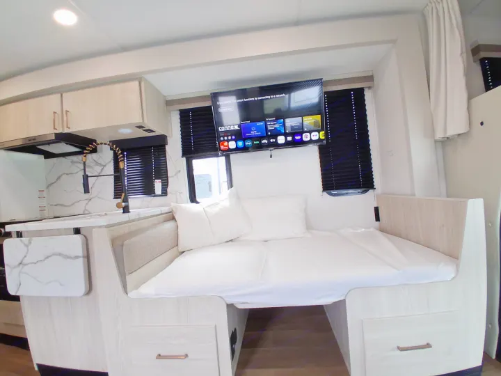 Modern RV rental interior featuring a compact kitchen, comfortable bed, and smart TV for your travels.. East to West Entrada 2027