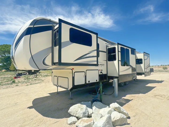 A modern K-Z Vango Gold fifth-wheel rv rental is parked at a sunny campsite with its slide-outs extended, ready for adventure.. K-Z Manufacturing Durango 2017