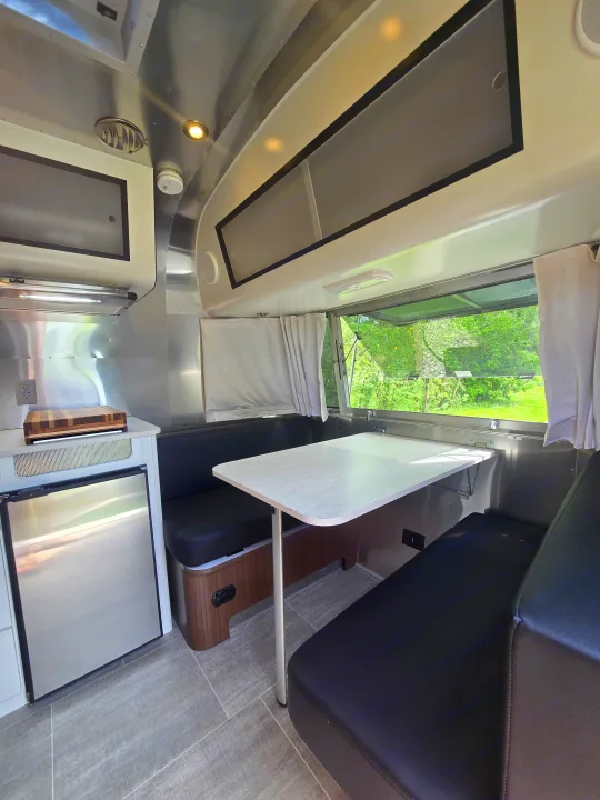 Compact Airstream RV rental interior with dinette, kitchenette, and scenic window view for your road trip adventure.. Airstream Caraval 2021