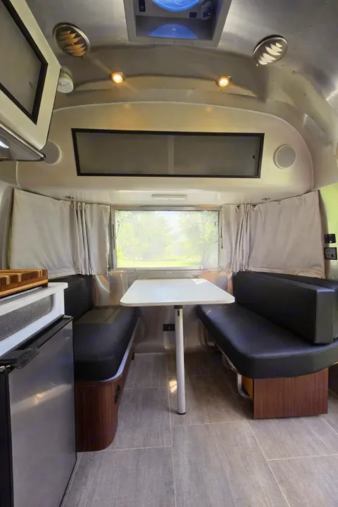 Spacious RV rental dinette with cozy seating, modern table, and scenic window view. Perfect for travel adventures.. Airstream Caraval 2021