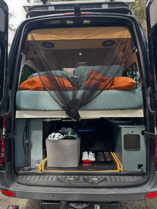 Inside this RV rental: a comfortable bed with bug net, smart storage for bike gear & helmets, perfect for adventures.. Mercedes Sprinter 2007