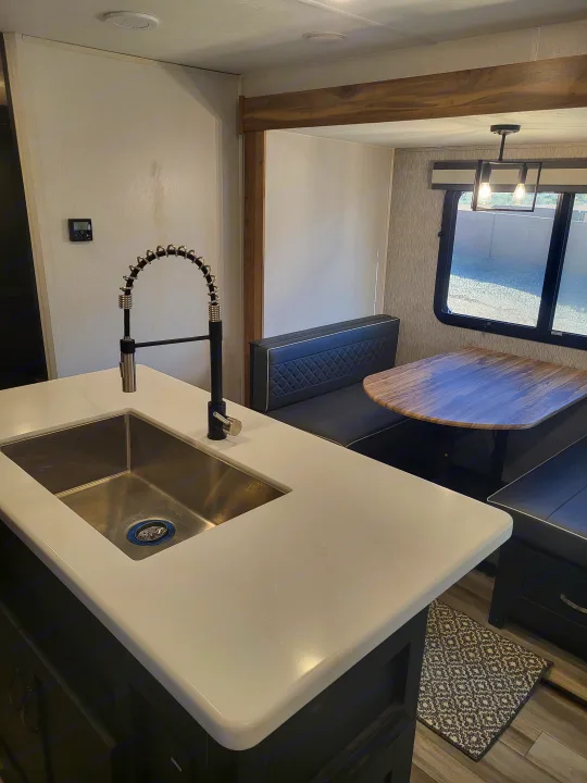 Experience comfort in this RV rental featuring a stylish kitchen island, sink, and cozy dinette with window view.. Coachmen Freedom Express liberty edition 326bhdsle 2023