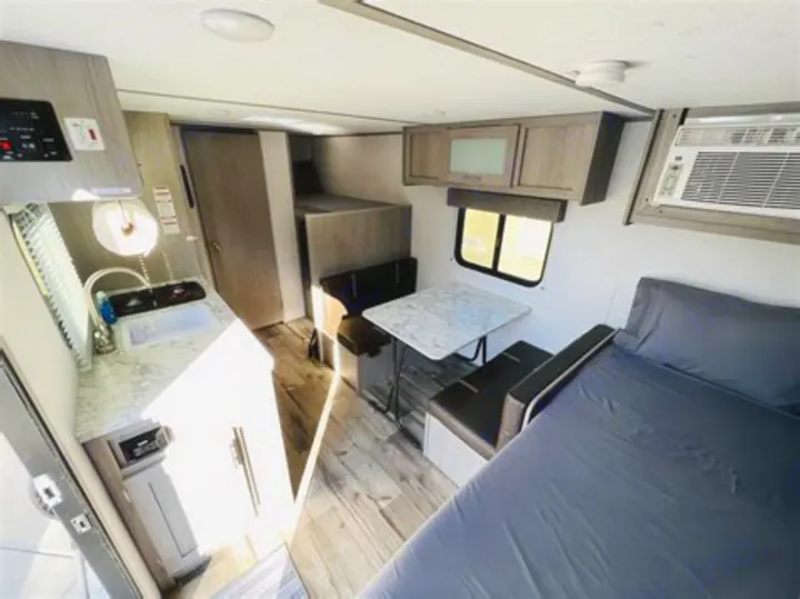 rv rental: Compact interior with kitchenette, dinette, bed, bunk beds, and AC unit visible.. Coleman Lantern 2023
