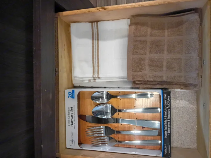 A neatly organized drawer in an rv rental, featuring a 20-piece flatware set for 4 and folded towels.. Keystone RV Springdale 2019