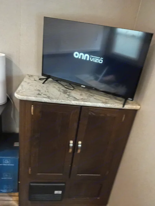 RV rental entertainment setup: A TV with an "onn Vizio" logo on a marble-look counter above a dark wood cabinet.. Keystone RV Springdale 2019