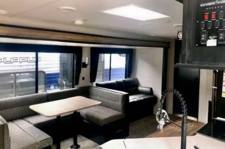 This RV rental interior shows a U-shaped dinette, table, sofa, kitchen faucet, and large windows. Ideal for travel.. Forest River Cherokee 2021