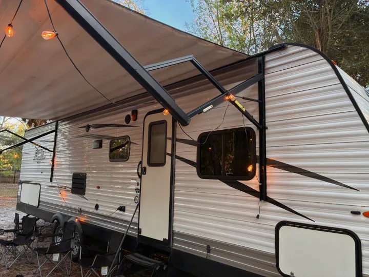 An RV rental with an extended awning, string lights, and camping chairs offers a cozy outdoor experience.. Jayco Jay Flight SLX 2017