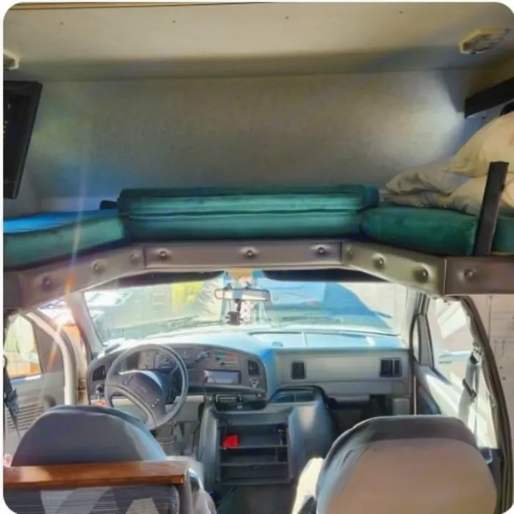 RV rental interior: Cab-over bed above the driver's cabin, showing dashboard and front seats.. Ford Ford E350 1996