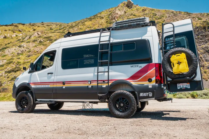 Storyteller Overland Mode 4x4 adventure van, fully equipped for off-road rv rental trips, parked by a sunny hill.. Storyteller Overland Storyteller Overland Class B 2022