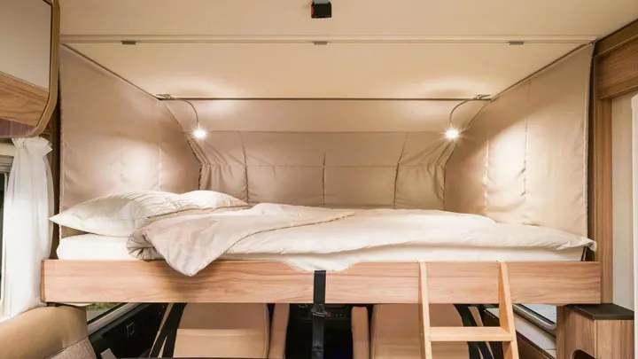 Get a great night's sleep in this RV rental's clever drop-down bed with cozy bedding and reading lights.. HYMER EXISIS I 474 2025