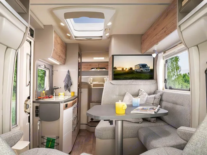 Modern rv rental interior with a cozy dinette, kitchen, TV, and bright skylight, perfect for comfortable journeys.. HYMER EXISIS I 474 2025