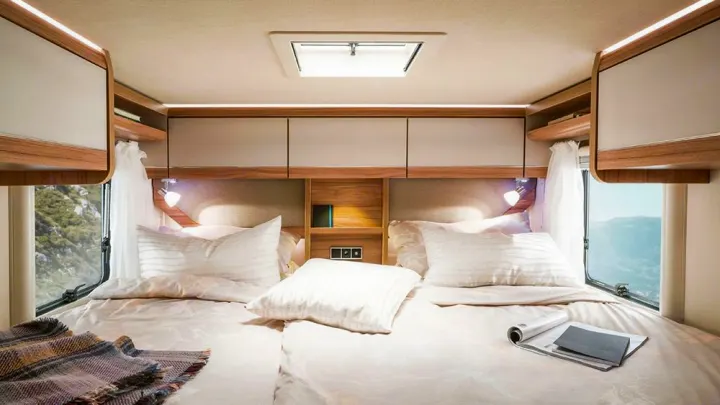 Experience comfort in this RV rental bedroom: cozy twin beds, overhead storage, and scenic views through large windows.. HYMER EXISIS I 474 2025