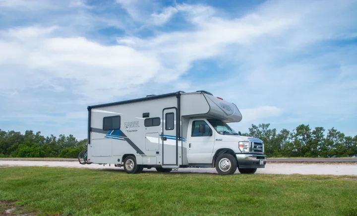 White & gray Class C rv rental (Coachmen Cross Trail) parked on grass under a cloudy sky. Ready for your next adventure.. Coachmen Cross Trail 2023