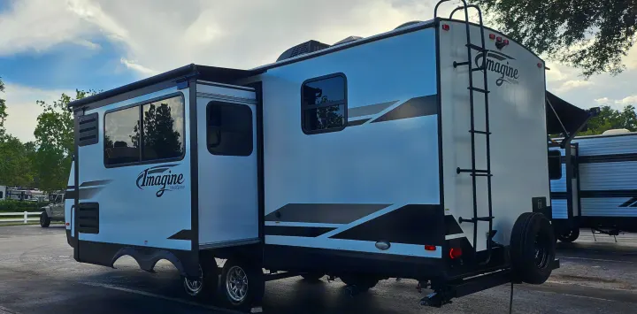 This modern white Grand Design Imagine travel trailer, with extended slide-out and awning, is perfect for an RV rental adventure.. Grand Design Imagine 2021