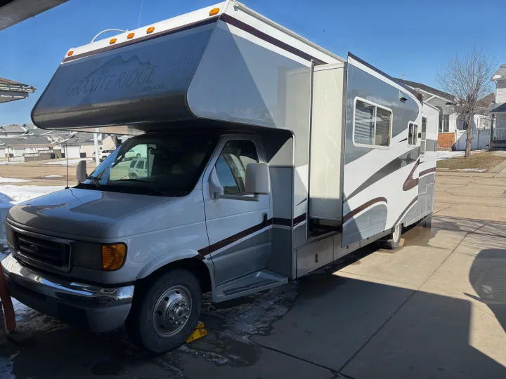 Granite Ridge by Jayco Class C rv rental with its slide-out extended, parked on a concrete driveway.. Jayco Granite Ridge 2004