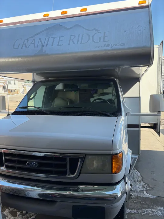 A white Ford-based Jayco Granite Ridge rv rental (Class C motorhome) parked outdoors, front view.. Jayco Granite Ridge 2004