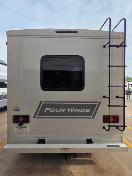 Rear of a white Four Winds RV rental. Features a ladder, window, taillights, bumper, and hitch receiver.. Four Winds 31E 2026