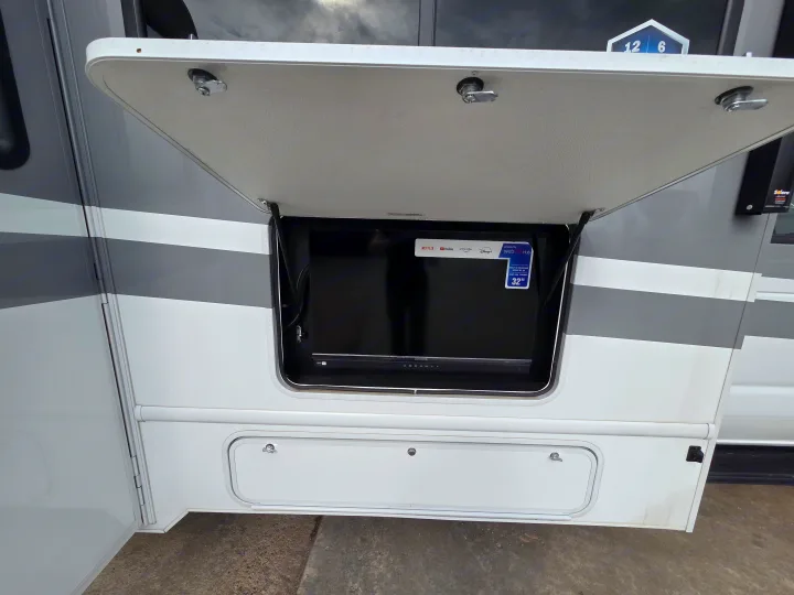 This RV rental features an outdoor entertainment setup: a 32" smart TV with Netflix, YouTube, JBL soundbar, and storage below.. Four Winds 31E 2026
