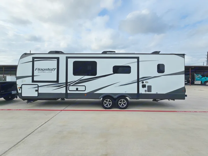 Modern Flagstaff Super Lite travel trailer for RV rental. White with black/grey graphics, parked on concrete. Perfect for camping!. Forest River Flagstaff Super Lite 2022
