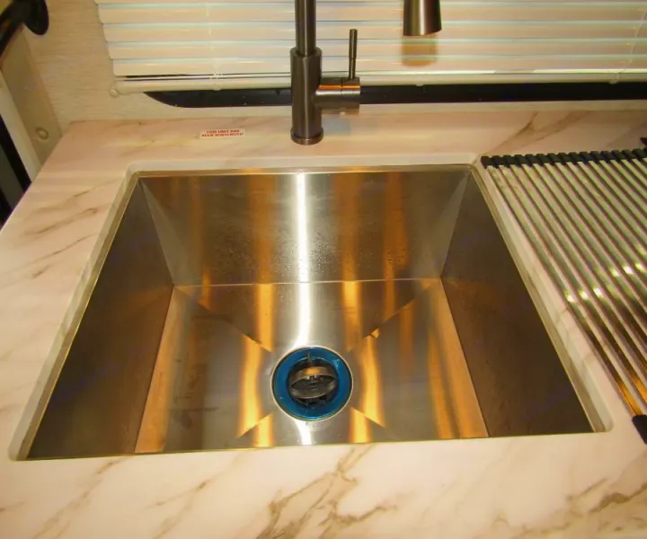 RV rental kitchen: stainless steel sink, modern faucet, marble-look countertop, and drying rack. Unit has been winterized.. Thor Chateau 2025
