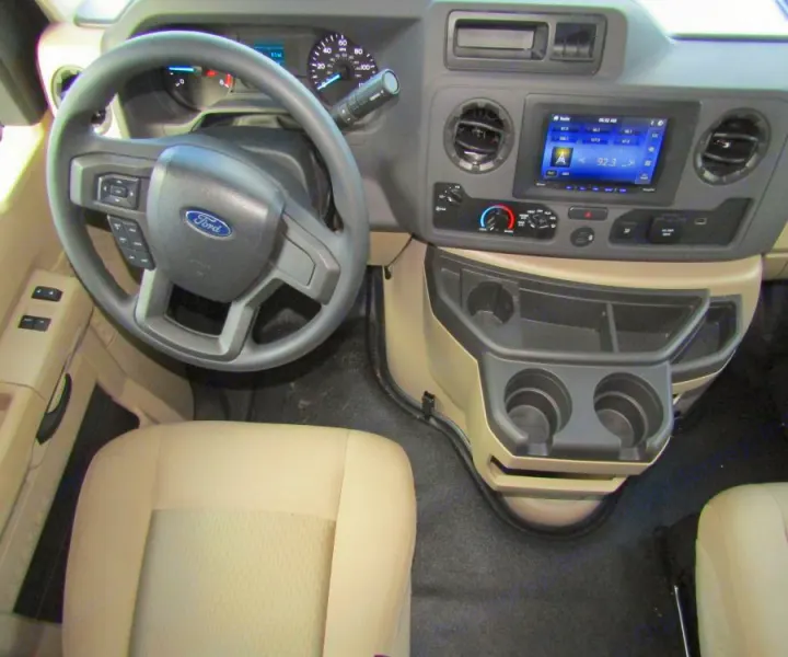 Spacious RV rental driver's area featuring a Ford steering wheel, dashboard, media screen, and center console with cup holders.. Thor Chateau 2025