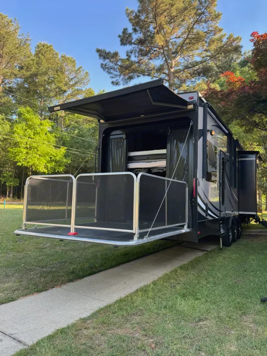 RV rental: A toy hauler with an open rear deck, extended awning, and convertible bunk beds, parked on a driveway.. Jayco Seismic 2016