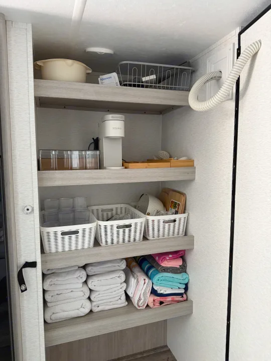 Organized rv rental cabinet: shelves hold kitchenware, a Keurig, and neatly stacked towels. Compact living space.. Crossroads RV Sunset Trail Sport 2025