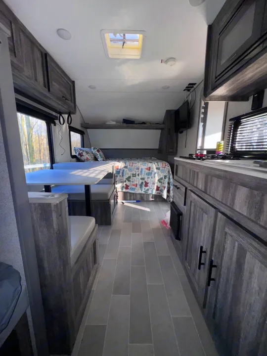 Inside an rv rental: a compact living space featuring a dinette, bed, and kitchenette with modern grey finishes and bright windows.. Forest River Salem FSX 2020