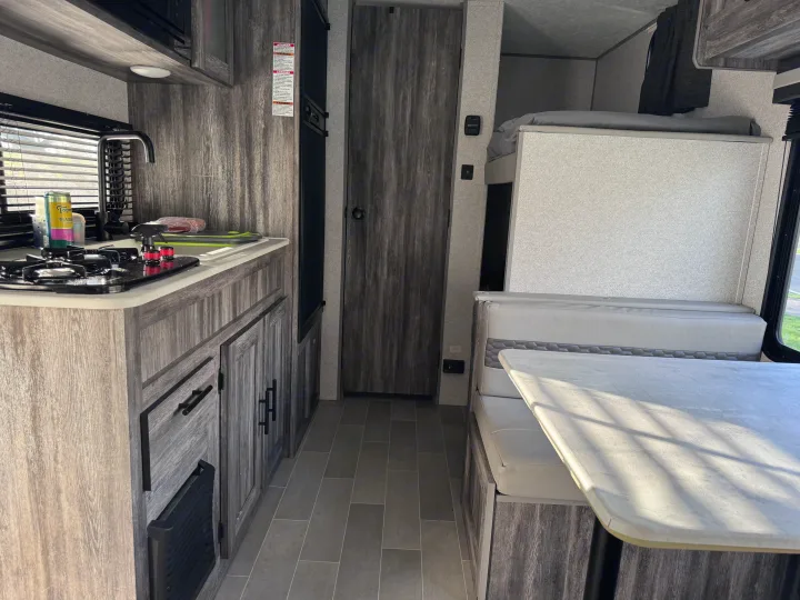 Modern rv rental interior showcasing a full kitchen, dining area with a table, and cozy bunk beds. Perfect for family adventures.. Forest River Salem FSX 2020