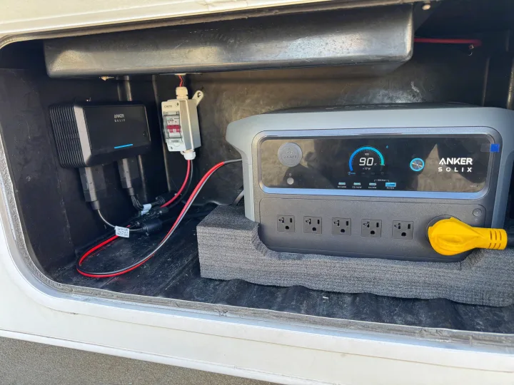RV rental power: Anker Solix portable power station (90% charged) with connected charging system and outlets in a storage bay.. Four Winds 5000 2008