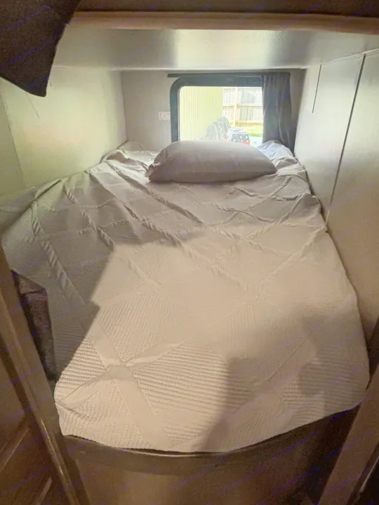 Cozy RV rental sleeping area with a grey bed & pillow, window view, and visible EXIT sign.. Jayco Jay Flight 2020