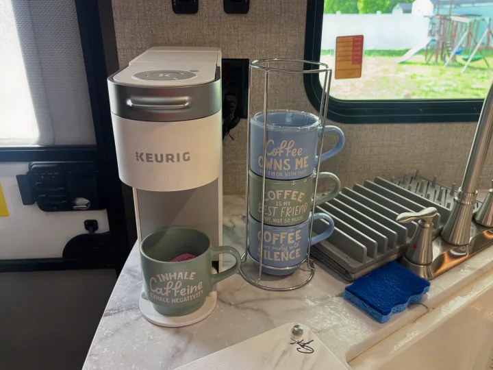 RV rental kitchen featuring a Keurig coffee maker, a stack of coffee mugs, and a sink area for a cozy morning.. Jayco Jay Flight 2020