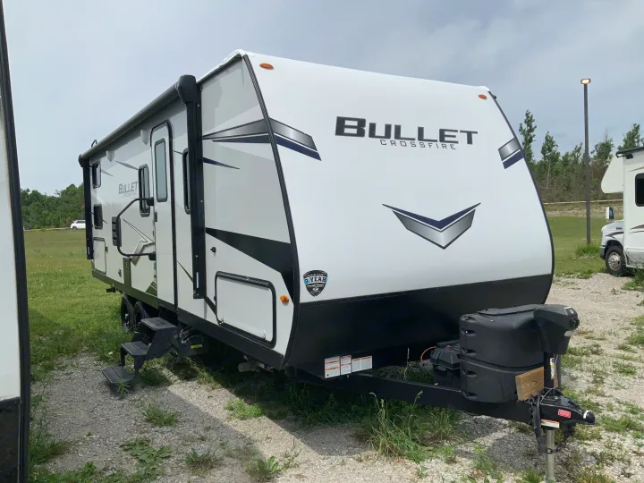 This white Bullet Crossfire travel trailer, perfect for an RV rental, is parked on a gravel lot, ready for your next adventure.. Keystone RV Bullet Crossfire 2022