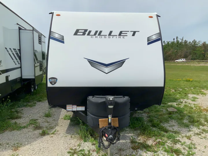 Front of a white Bullet Crossfire travel trailer, ideal for an RV rental, showing the hitch and propane tank.. Keystone RV Bullet Crossfire 2022