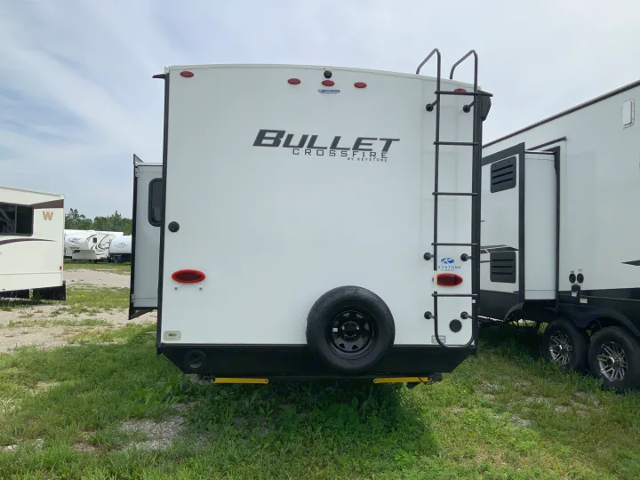 Travel trailer for RV rental. Rear view of a Keystone Bullet Crossfire with ladder, spare tire, and taillights.. Keystone RV Bullet Crossfire 2022